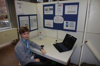 Der Erstplatzierte Pit Voigtsberger sitz vor einem Notebook an seinem Projektstand