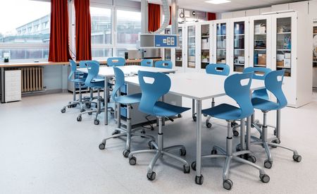 Moderner SFZ-Raum mit einem großen Tisch und mehreren blauen Stühlen, umgeben von Schränken mit Laborgeräten.