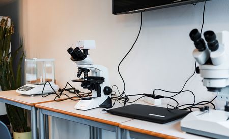 Zwei Mikroskope, eine Feinwagae und ein Laptop auf einem Tisch in einem Labor des Schülerforschungszentrums.