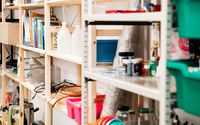 Holzregale, gefüllt mit Büchern, Behältern und verschiedenen Laborutensilien zum Forschen und Experimentieren.