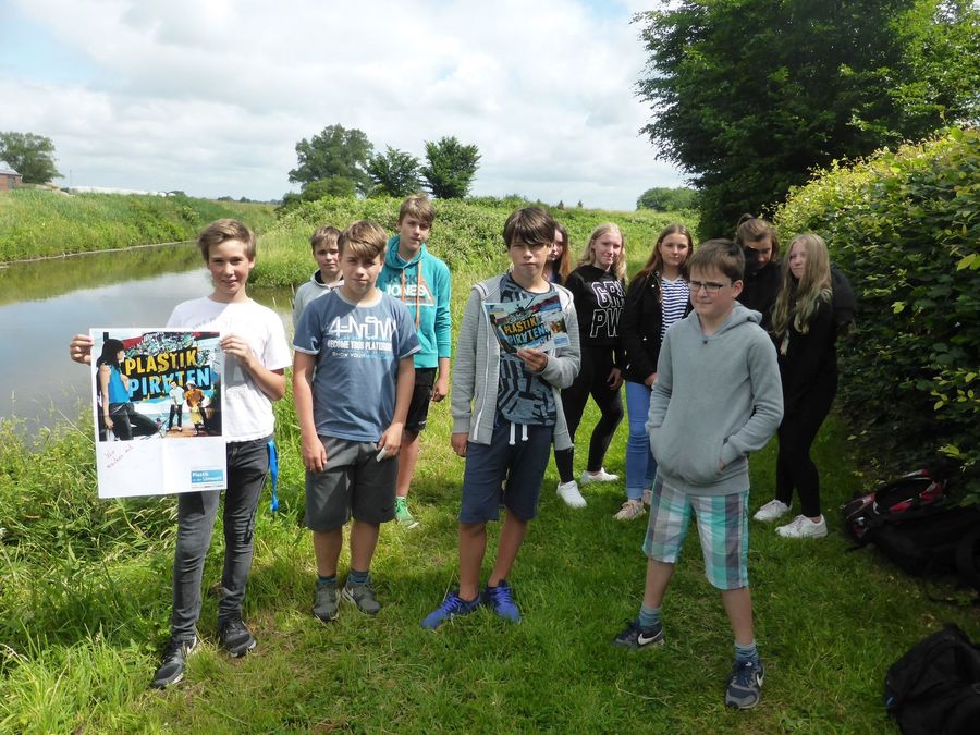 Schülerinnen und Schüler stehen an der Miele und halten ein Plakat der Plastikpiraten hoch