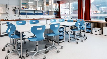 Moderner SFZ-Raum mit einem großen Tisch und mehreren blauen Stühlen, umgeben von Schränken mit Laborgeräten.