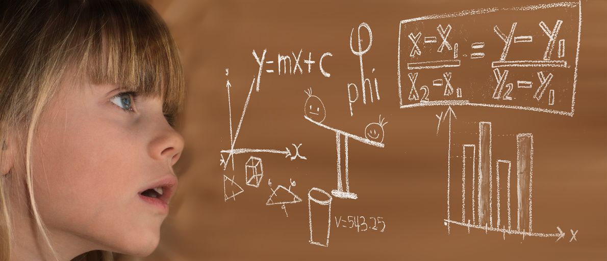 Ein Mädchen blikt auf mathematische Formeln an der Tafel.